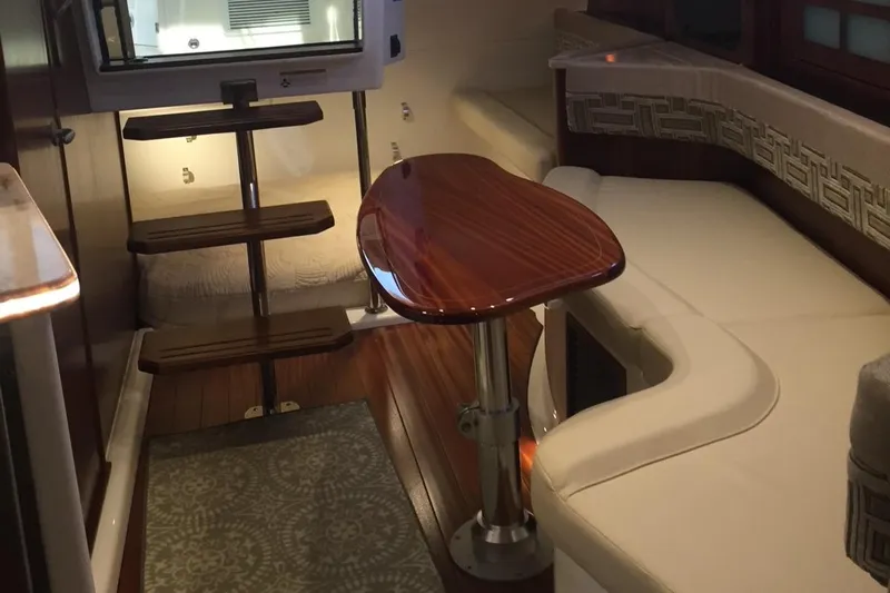  Yacht Photos Pics 2021 Pursuit OS 385 Offshore cabin interior with wooden table and seating.