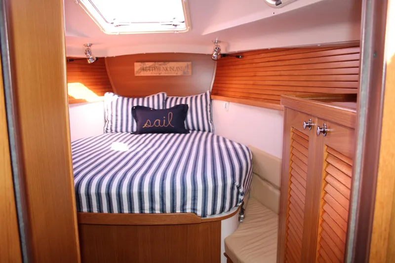 Hannah Yacht Photos Pics Cozy cabin interior of 2011 Catalina 445 sailboat with striped bedding and wooden accents.