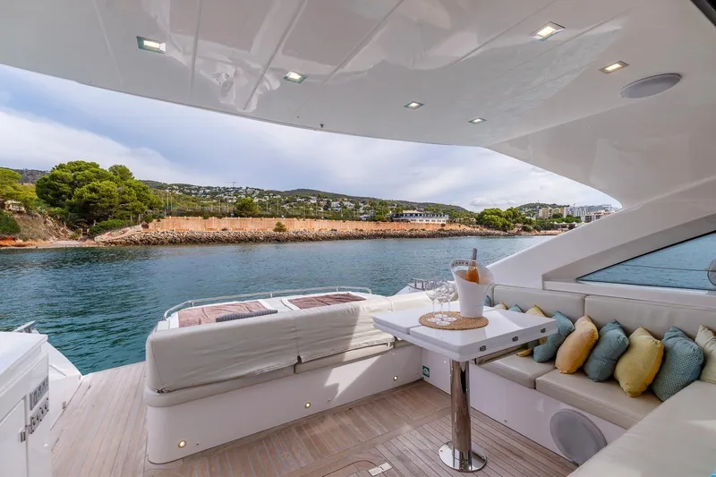  Yacht Photos Pics Luxurious 2020 Filippetti S55S yacht deck with seating, table, and scenic waterfront view.