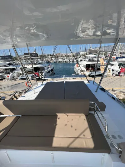  Yacht Photos Pics 2023 Bali 4.6 yacht with sunbathing area, docked at a marina with multiple boats.