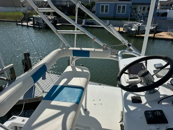  Yacht Photos Pics 2000 Cabo 31 Express boat helm with steering wheel and seating, docked by waterfront homes.