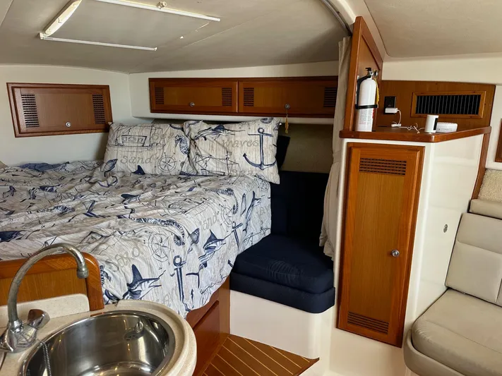  Yacht Photos Pics Cabo 31 Express 2000 cabin interior with nautical bedding and wooden cabinetry.