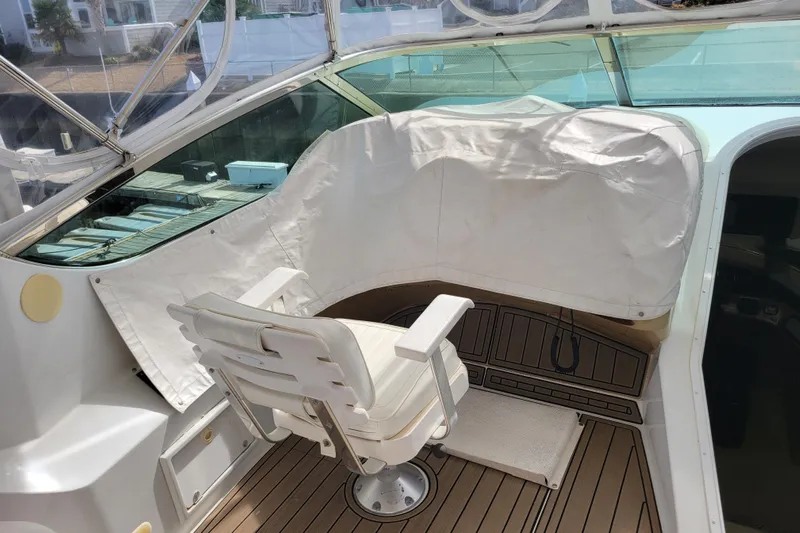  Yacht Photos Pics Captain's chair on 2001 Carver 570 Voyager Pilothouse, featuring teak flooring and covered controls.