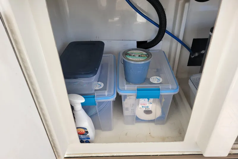  Yacht Photos Pics Storage compartment on a 2001 Carver 570 Voyager Pilothouse with plastic containers and cleaning supplies.