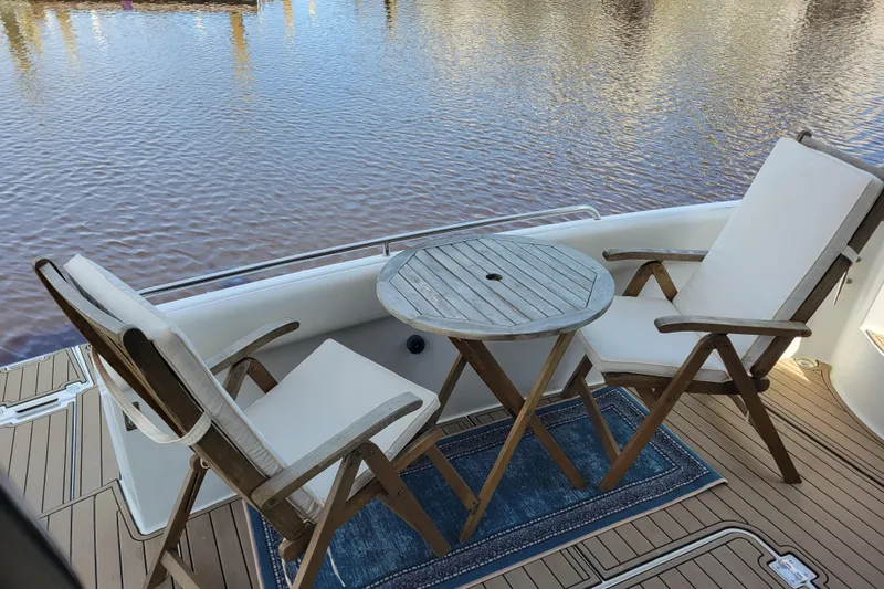  Yacht Photos Pics Deck seating area on 2001 Carver 570 Voyager Pilothouse with chairs and table by the water.