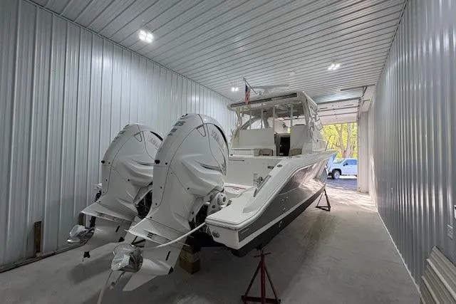 Yacht Photos Pics 2021 Pursuit OS 355 Offshore boat with dual engines in a storage facility.