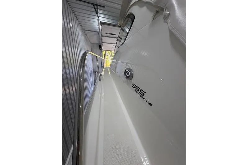  Yacht Photos Pics 2021 Pursuit OS 355 Offshore boat in storage, side view with branding visible.