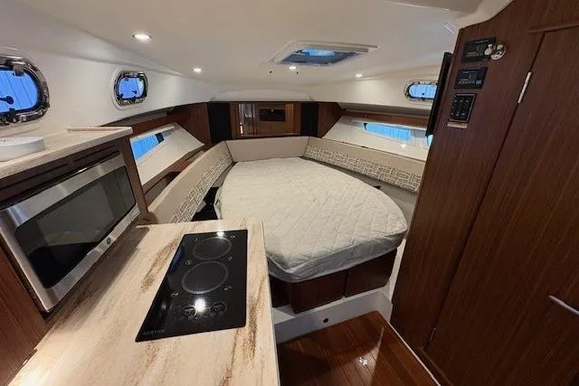  Yacht Photos Pics 2021 Pursuit OS 355 Offshore cabin interior with bed, stove, and microwave.