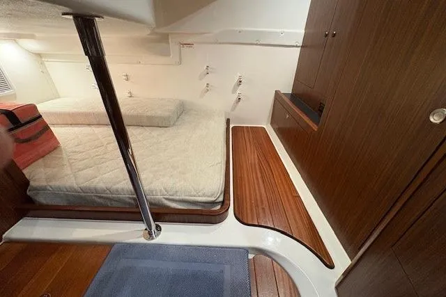  Yacht Photos Pics 2021 Pursuit OS 355 Offshore cabin interior with bed, wooden flooring, and storage cabinets.