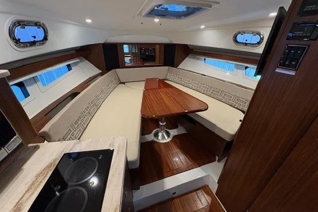  Yacht Photos Pics 2021 Pursuit OS 355 Offshore cabin with elegant seating and wooden table.