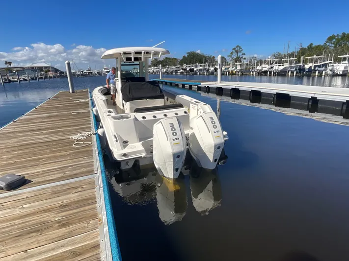  Yacht Photos Pics 2023 Boston Whaler 280 Outrage docked, featuring twin Mercury V8 engines, under clear blue skies.