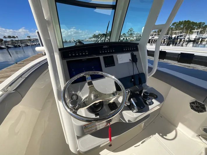  Yacht Photos Pics 2023 Boston Whaler 280 Outrage helm with steering wheel and controls, docked at marina.