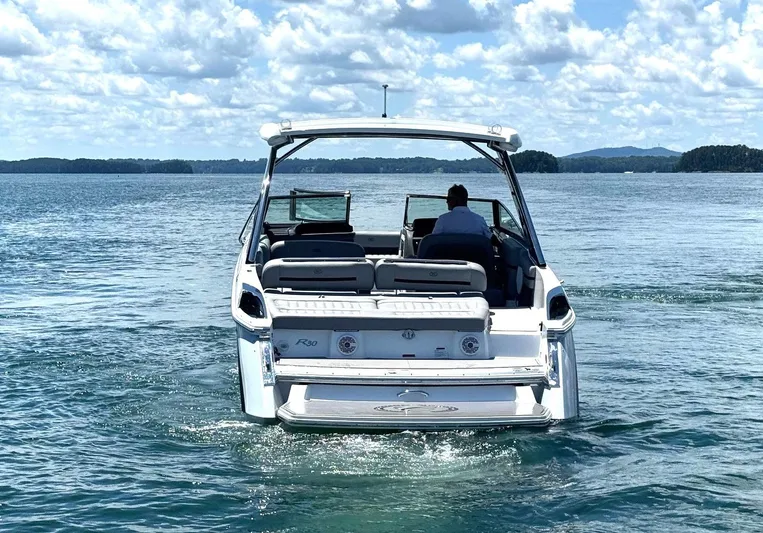  Yacht Photos Pics 2022 Cobalt R30 boat cruising on a serene lake under a partly cloudy sky.