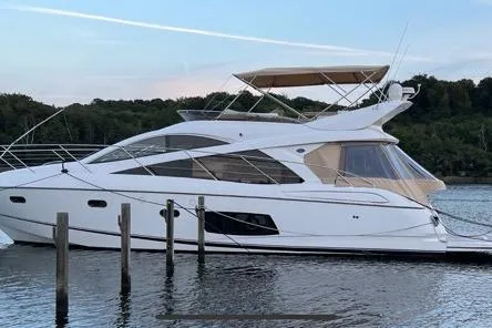  Yacht Photos Pics 2012 Sunseeker Manhattan 53 yacht docked on calm water, surrounded by trees.