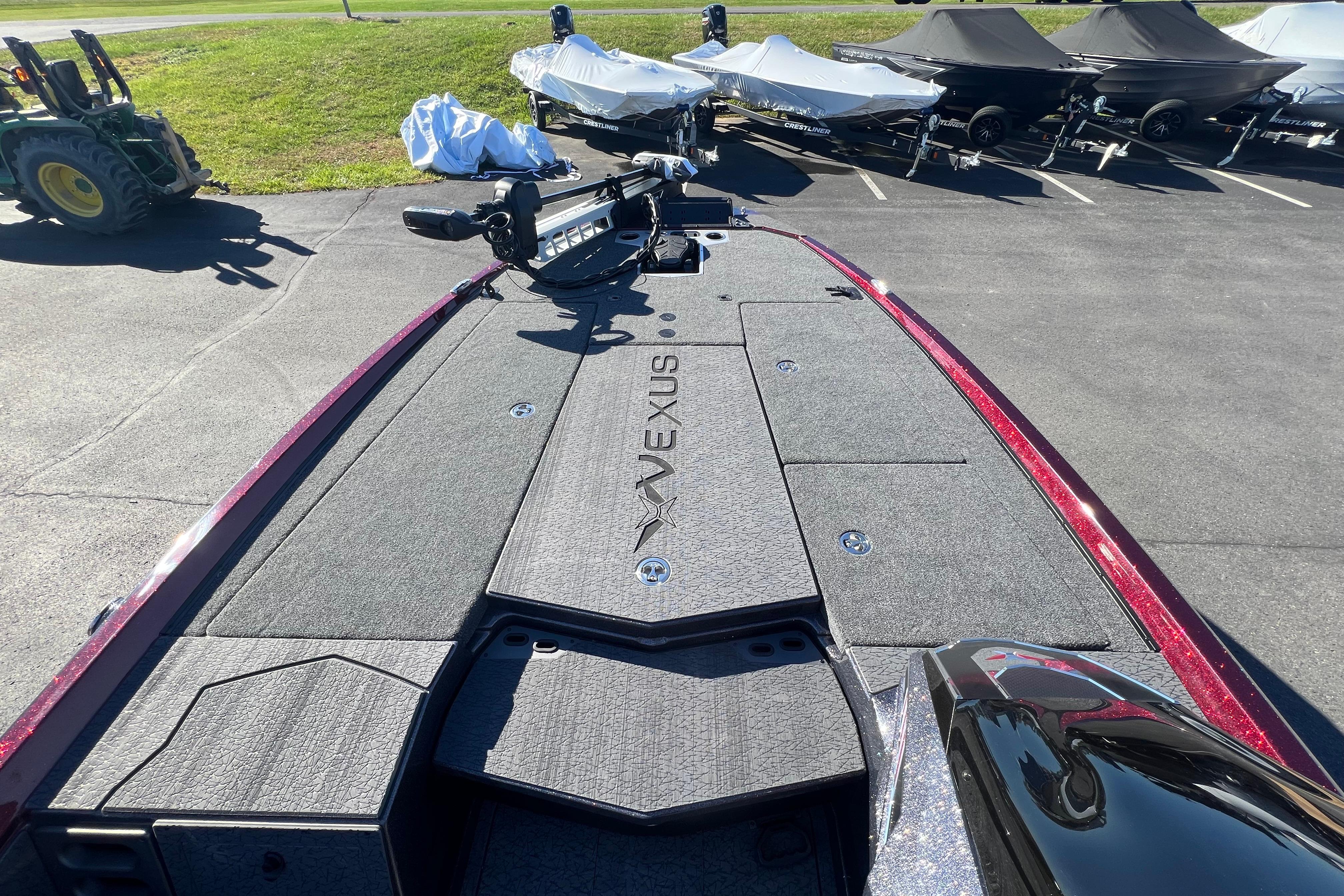 2026 Vexus VXS20 boat deck with storage compartments and trolling motor, parked outdoors.