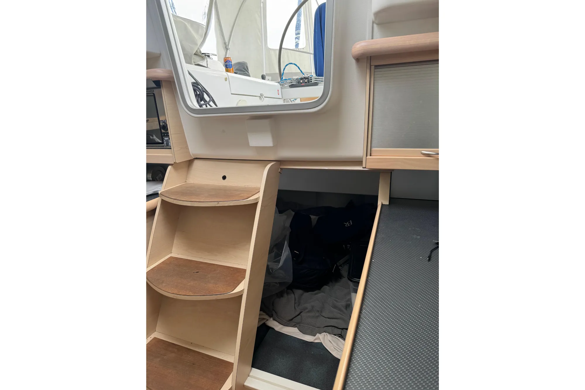 Interior of a 2016 Dragonfly 32 sailboat, featuring wooden steps and storage area.