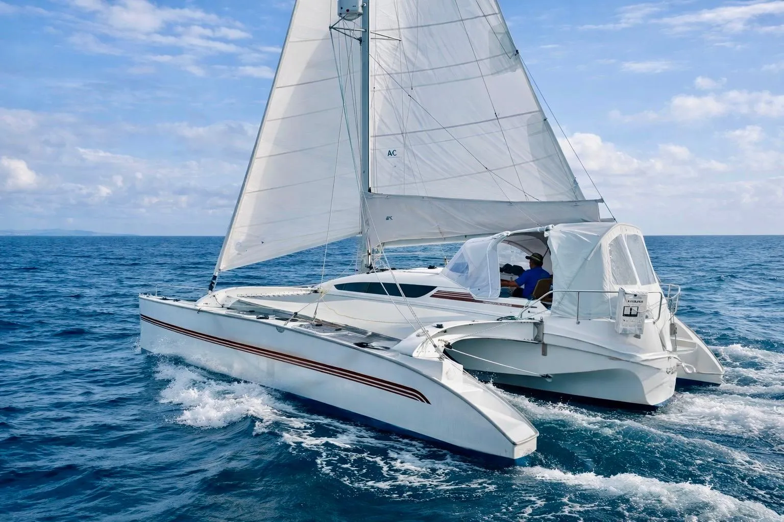 Sailing on open sea, 2016 Dragonfly 32 trimaran with white sails and blue sky.