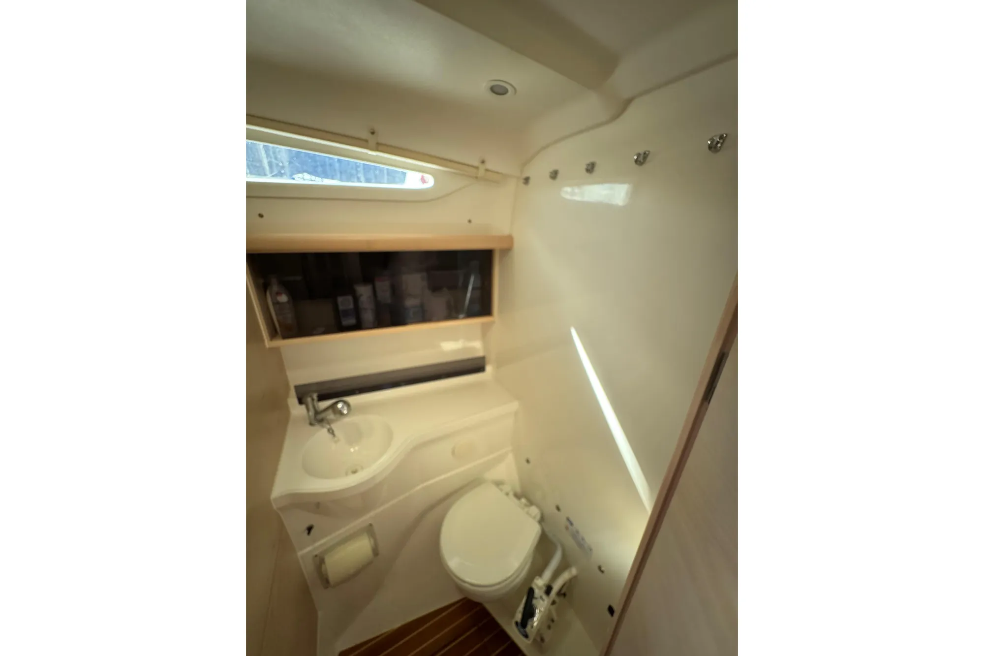 Compact bathroom in 2016 Dragonfly 32 sailboat with sink, toilet, and storage.