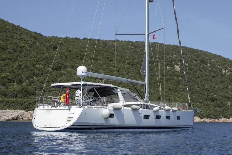  Yacht Photos Pics 2020 Jeanneau 64 yacht sailing near a lush, green coastline.