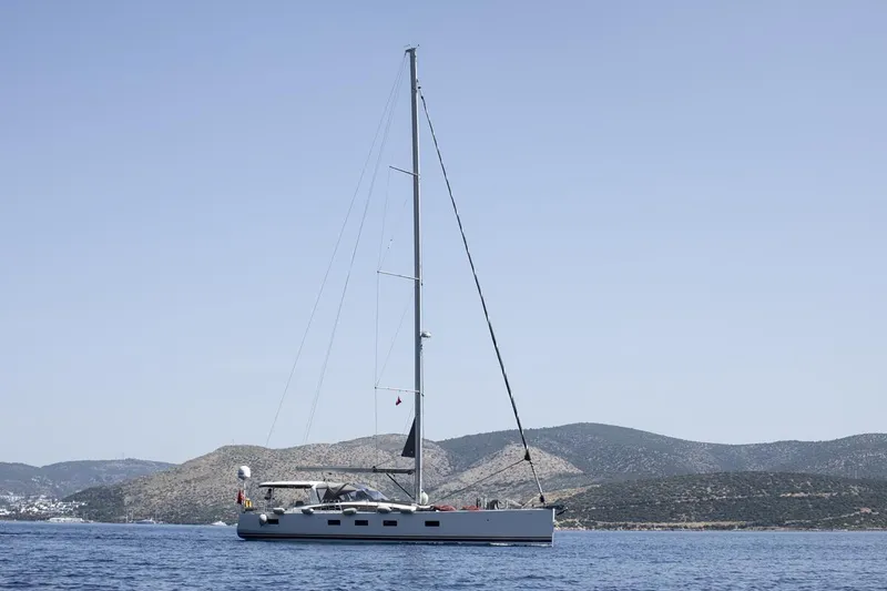  Yacht Photos Pics 2020 Jeanneau 64 yacht sailing near coastal hills under clear sky.