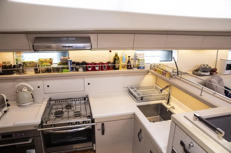  Yacht Photos Pics Modern kitchen in a 2020 Jeanneau 64 yacht with stove, sink, and storage.