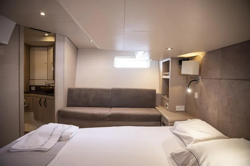 Yacht Photos Pics Luxurious interior of 2020 Jeanneau 64 yacht cabin with bed, sofa, and bathroom.