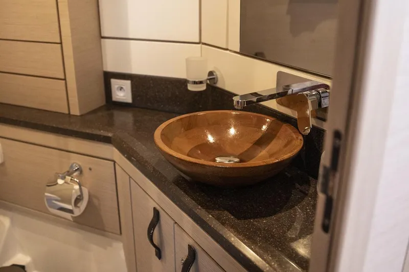  Yacht Photos Pics Luxurious bathroom sink in 2020 Jeanneau 64 yacht, featuring elegant wood basin and modern fixtures.