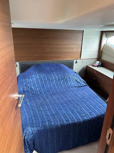  Yacht Photos Pics 2021 Princess V50 Open yacht bedroom with blue bedding and wooden accents.
