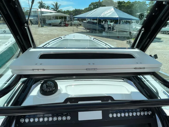 #339 White Yacht Photos Pics 2023 Everglades 273CC boat dashboard with compass and control panel, docked under a canopy.