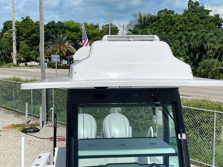 #339 White Yacht Photos Pics 2023 Everglades 273CC boat with T-top, parked outdoors, American flag in background.