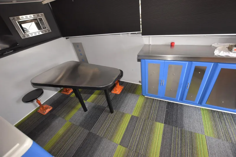 For Reel Yacht Photos Pics Interior of 1997 Viking 50 Convertible with modern table, blue cabinets, and striped flooring.