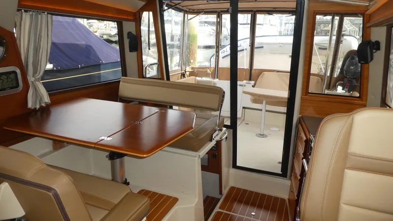 Second Act Yacht Photos Pics 2021 Ranger Tugs R-29 S interior with dining area and seating, featuring wood accents and large windows.
