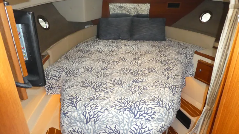 Second Act Yacht Photos Pics Cozy cabin interior of 2021 Ranger Tugs R-29 S with patterned bedding and porthole windows.