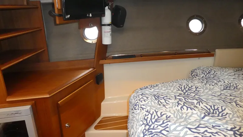 Second Act Yacht Photos Pics 2021 Ranger Tugs R-29 S interior cabin with bed, wooden shelves, and portholes.