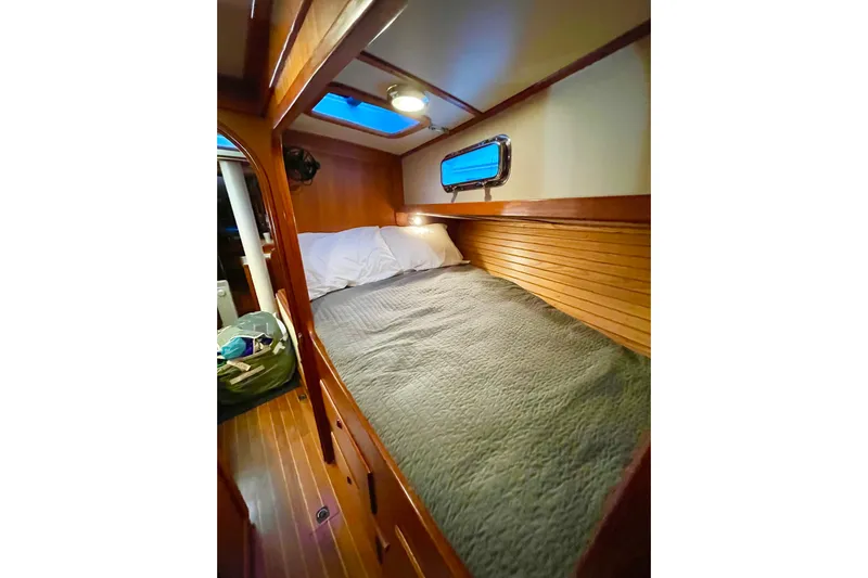 Skimmer Yacht Photos Pics Cozy cabin interior of 2000 Valiant 42 sailboat with wooden finish and bedding.