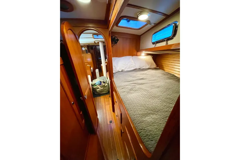 Skimmer Yacht Photos Pics Cozy cabin interior of 2000 Valiant 42 sailboat with wooden finish and comfortable bedding.