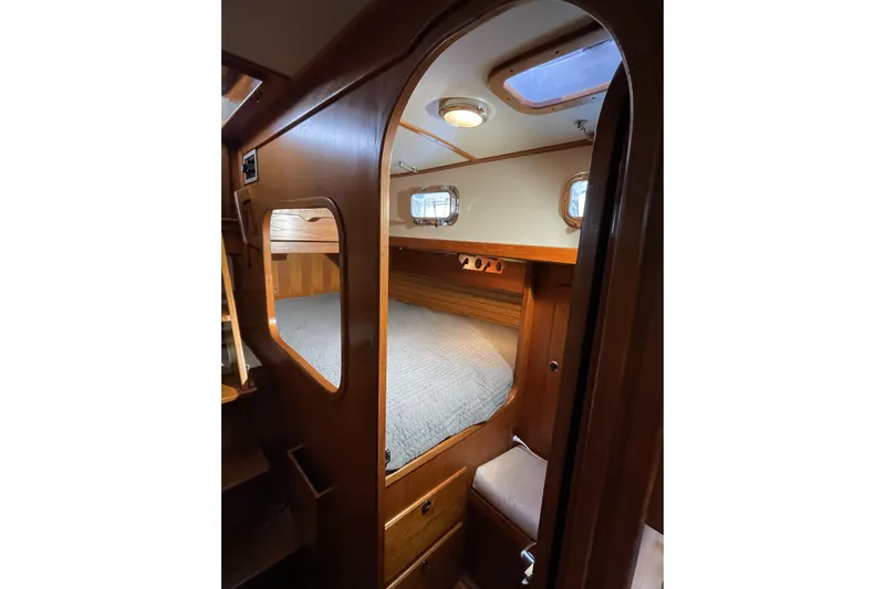 Skimmer Yacht Photos Pics Cozy cabin interior of 2000 Valiant 42 sailboat with wooden finish and porthole windows.