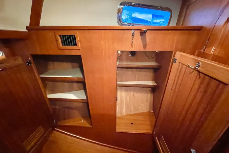 Skimmer Yacht Photos Pics Wooden interior storage cabinets on a 2000 Valiant 42 sailboat, featuring shelves and a porthole.