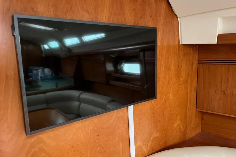 Arrow Yacht Photos Pics Interior of 2008 Jeanneau Sun Odyssey 45 yacht with mounted TV and wooden paneling.