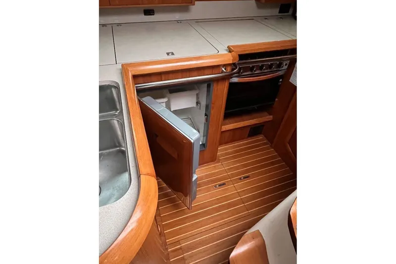 Arrow Yacht Photos Pics Interior of 2008 Jeanneau Sun Odyssey 45 yacht kitchen with open fridge and wooden flooring.