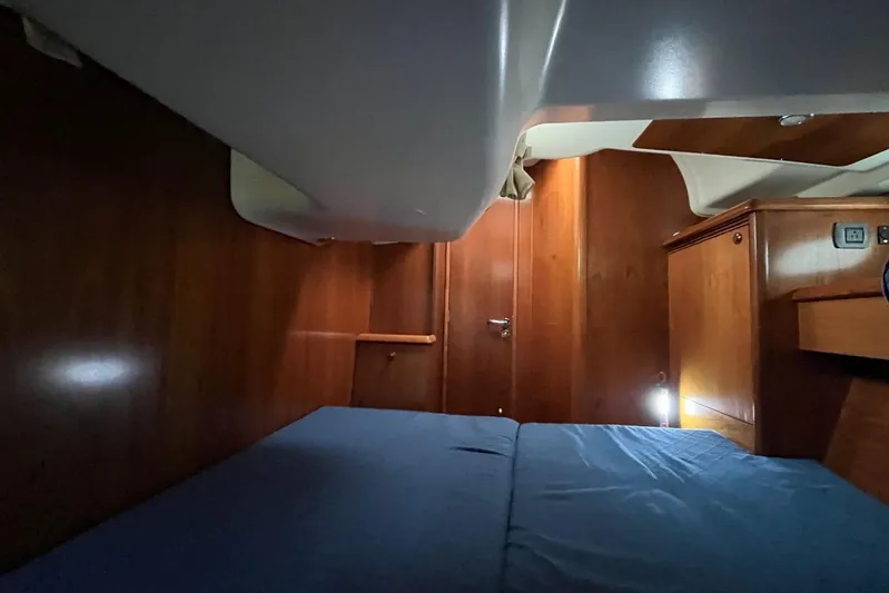 Arrow Yacht Photos Pics Interior cabin of 2008 Jeanneau Sun Odyssey 45 with wooden finish and blue bedding.
