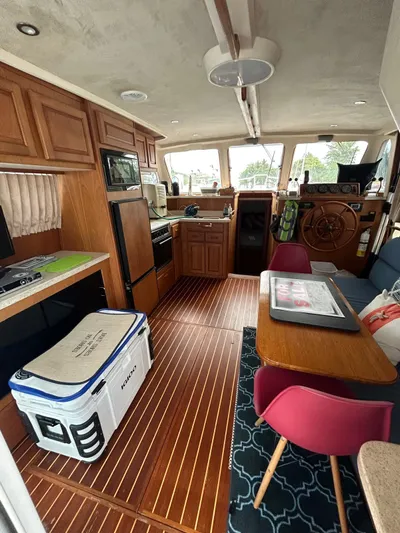  Yacht Photos Pics 1999 Mainship 350 Trawler interior with wood flooring, kitchenette, and helm station.