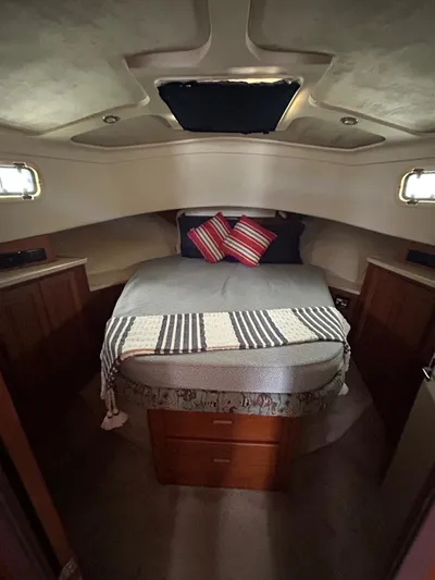  Yacht Photos Pics 1999 Mainship 350 Trawler cabin with cozy bed, striped blanket, and decorative pillows.