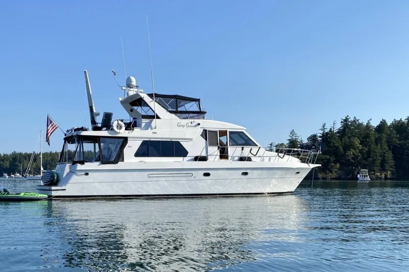 Grey Goose Yacht Photos Pics Compass 55 yacht from 2000 on calm water, surrounded by trees and boats.