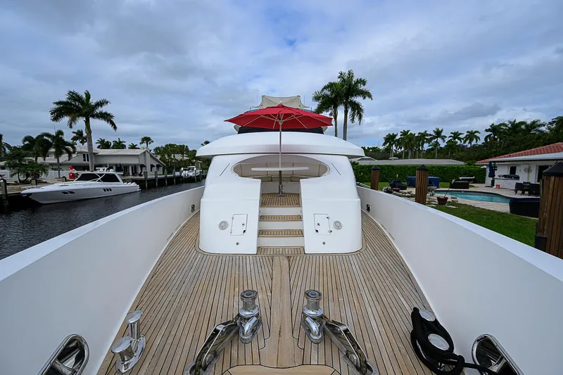 Scott Free Yacht Photos Pics Luxurious 2008 President Tri-Deck yacht with spacious deck and red umbrella, docked near palm trees.
