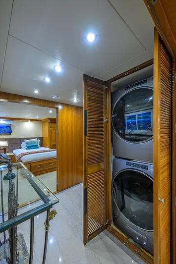 Scott Free Yacht Photos Pics Luxurious yacht interior with stacked washer and dryer, wooden cabinetry, and elegant bedroom.