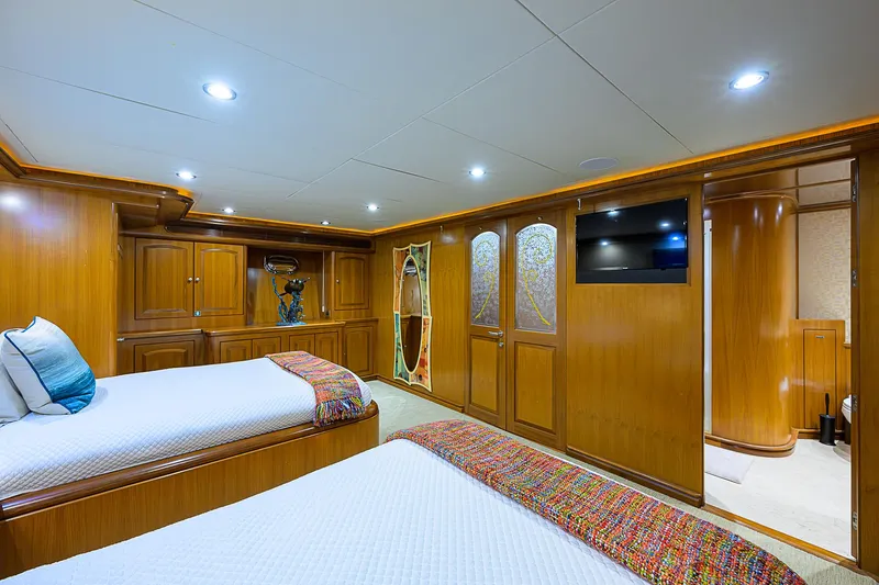Scott Free Yacht Photos Pics Luxurious 2008 President Tri-Deck yacht bedroom with twin beds and wooden cabinetry.