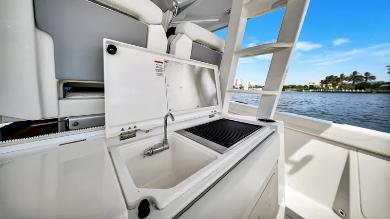 All Jack'd Up Yacht Photos Pics 2023 Pursuit S 428 Sport boat interior with sink and grill, overlooking water.