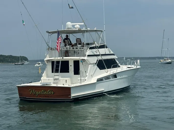 Negotiator Yacht Photos Pics 1994 Hatteras 54 Convertible yacht on calm water, rear view with American flag.