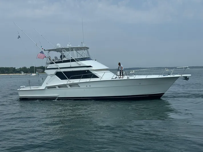 Negotiator Yacht Photos Pics 1994 Hatteras 54 Convertible yacht on calm water, featuring fishing rods and an American flag.